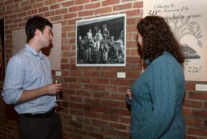 A man and a woman admiring a photograph hung on a brick wall